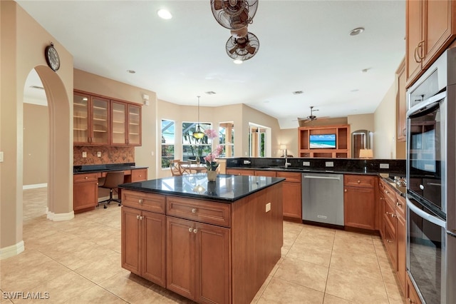 kitchen featuring tasteful backsplash, appliances with stainless steel finishes, a peninsula, light tile patterned flooring, and brown cabinetry