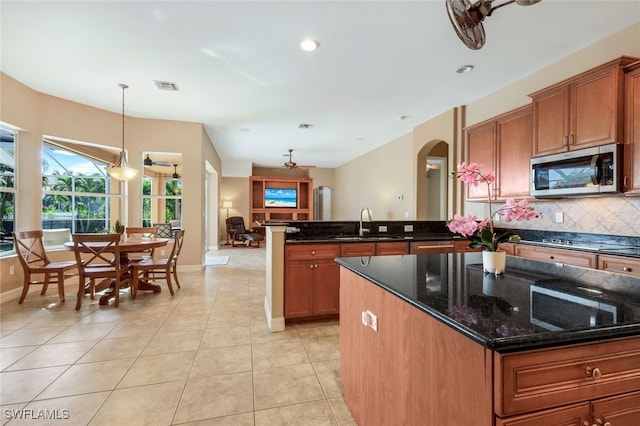 kitchen with stainless steel microwave, visible vents, decorative backsplash, brown cabinets, and a sink