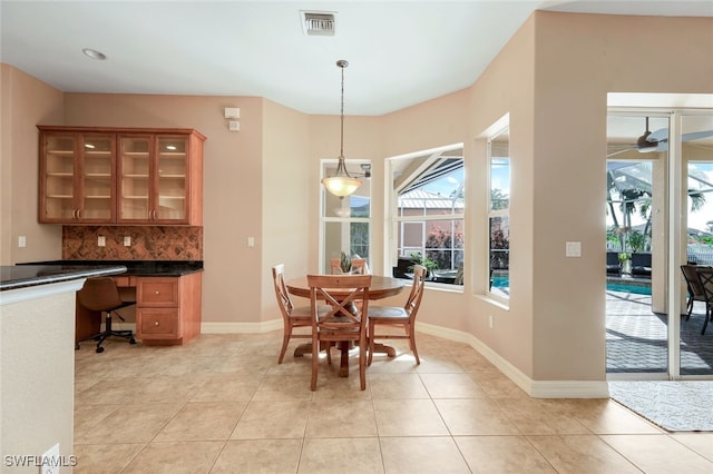 dining room featuring light tile patterned flooring, visible vents, built in study area, and baseboards