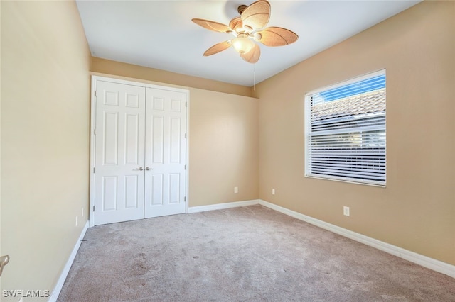 unfurnished bedroom featuring a closet, carpet floors, baseboards, and a ceiling fan