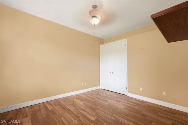 unfurnished bedroom with a closet, a ceiling fan, baseboards, and wood finished floors