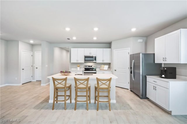 kitchen featuring a kitchen bar, light countertops, light wood finished floors, and stainless steel appliances