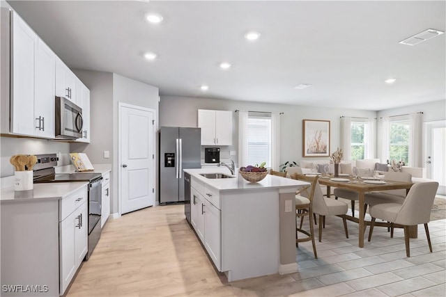 kitchen with visible vents, a sink, stainless steel appliances, light wood-style floors, and light countertops