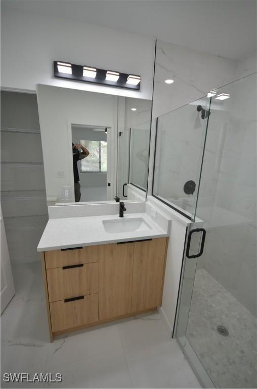 bathroom with vanity, a shower stall, and marble finish floor