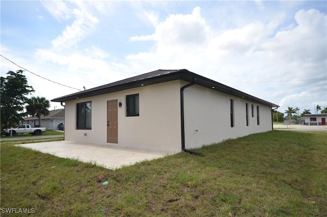 back of house featuring a patio area, stucco siding, and a lawn