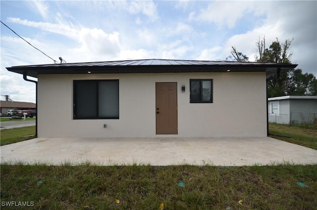 view of front of property with a standing seam roof, a patio, stucco siding, and metal roof