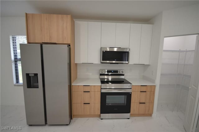 kitchen featuring light countertops, marble finish floor, and appliances with stainless steel finishes