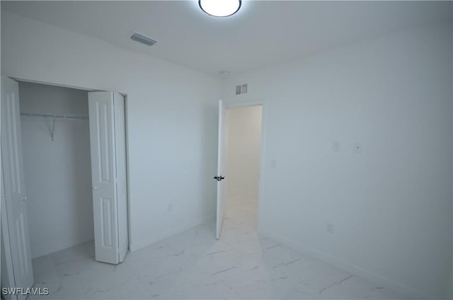 unfurnished bedroom featuring visible vents, marble finish floor, a closet, and baseboards