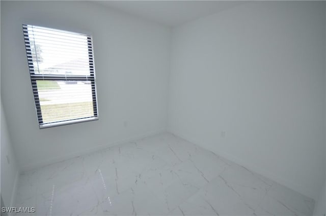 spare room with baseboards and marble finish floor