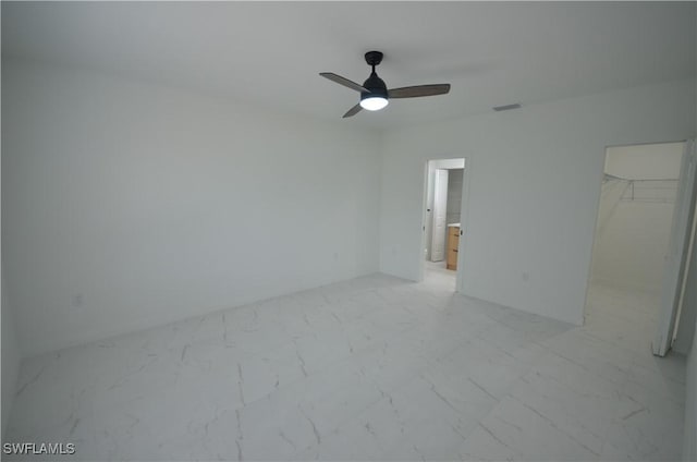 unfurnished bedroom featuring visible vents, a walk in closet, ceiling fan, a closet, and marble finish floor