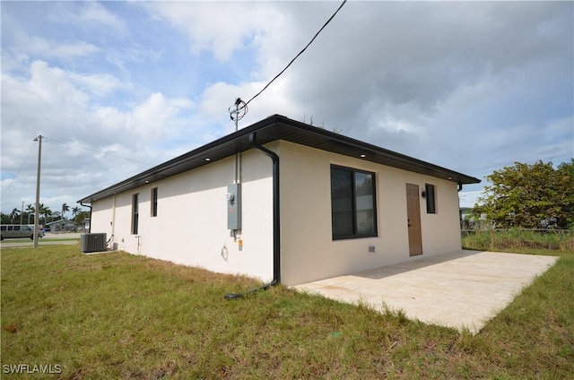 view of property exterior featuring a patio area, stucco siding, central AC, and a yard