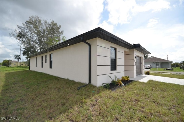 view of side of home with stucco siding, driveway, a lawn, and an attached garage