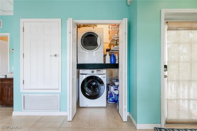 clothes washing area with laundry area, visible vents, stacked washer / drying machine, and tile patterned floors