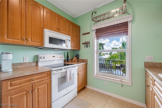 kitchen with crown molding, baseboards, light countertops, light tile patterned flooring, and white appliances