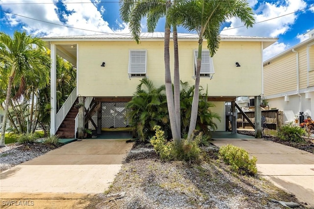 coastal home featuring stairs, a carport, driveway, and metal roof