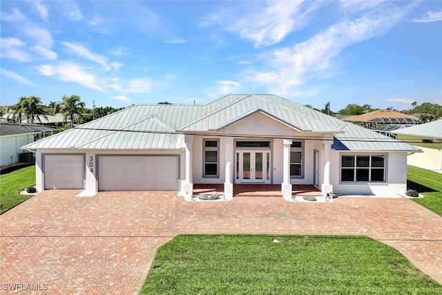 view of front of house with stucco siding, french doors, metal roof, decorative driveway, and a standing seam roof