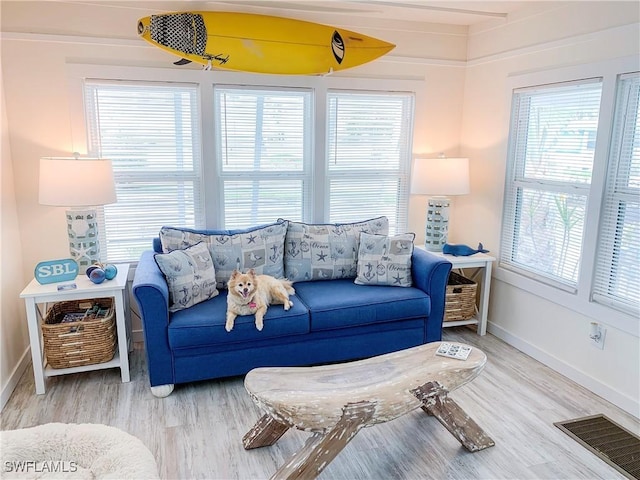 living area featuring plenty of natural light, wood finished floors, visible vents, and baseboards