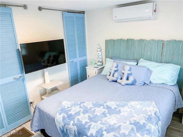 bedroom featuring a closet, an AC wall unit, and wood finished floors