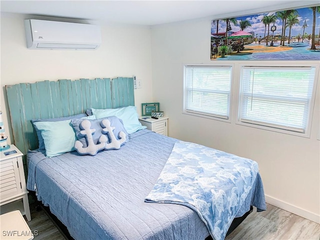 bedroom with a wall mounted air conditioner, baseboards, and wood finished floors