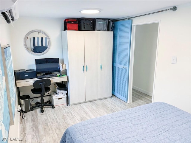 bedroom featuring a wall mounted air conditioner and wood finished floors