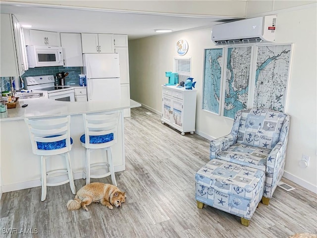 kitchen featuring white appliances, visible vents, a wall mounted air conditioner, light wood-type flooring, and backsplash