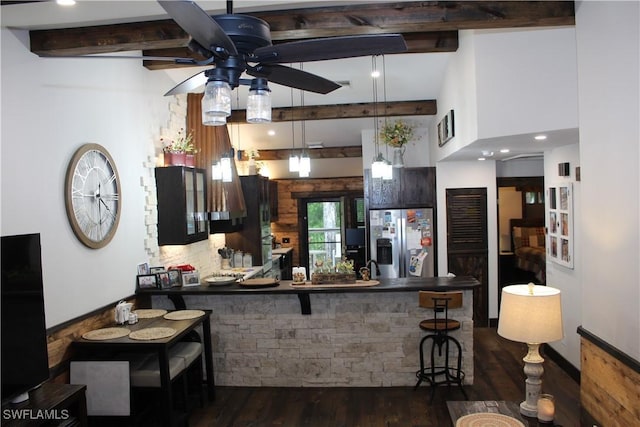 kitchen featuring dark wood-type flooring, beamed ceiling, a kitchen breakfast bar, stainless steel refrigerator with ice dispenser, and a ceiling fan