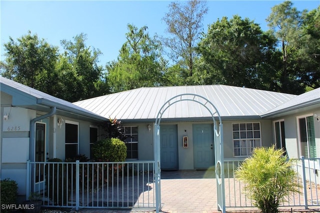 exterior space featuring stucco siding, metal roof, a standing seam roof, and fence