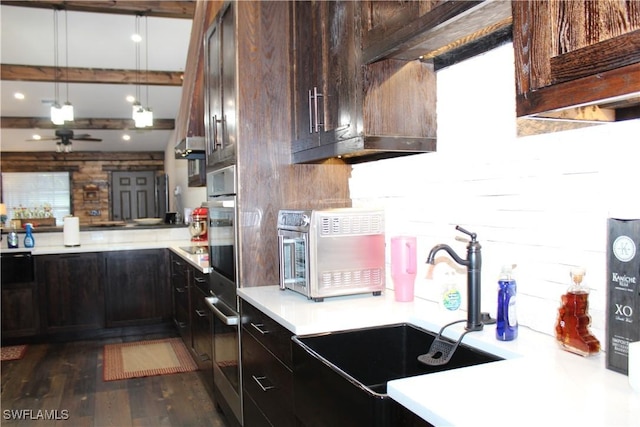 kitchen featuring a sink, decorative light fixtures, dark wood-style floors, dark brown cabinetry, and light countertops