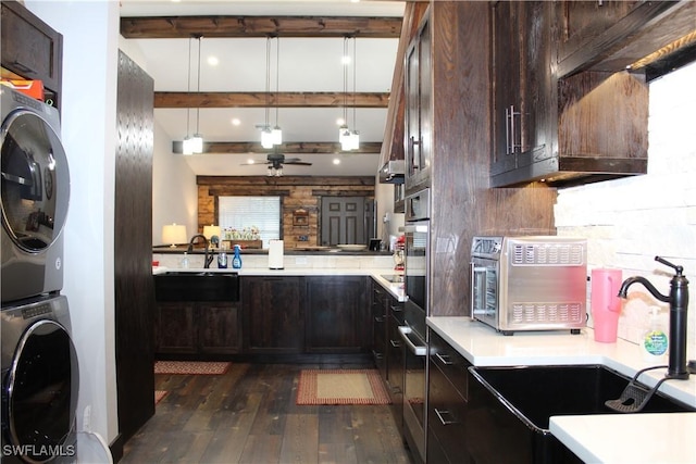 kitchen featuring a sink, beamed ceiling, dark brown cabinets, and stacked washing maching and dryer