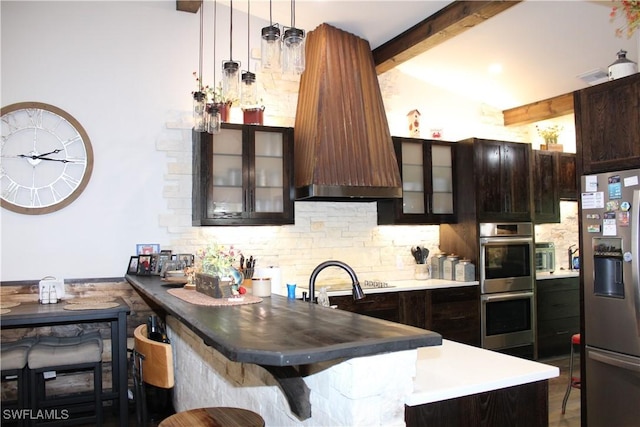 kitchen featuring stainless steel appliances, dark brown cabinetry, glass insert cabinets, beamed ceiling, and backsplash