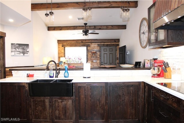 kitchen with beam ceiling, under cabinet range hood, a sink, dark brown cabinetry, and light countertops