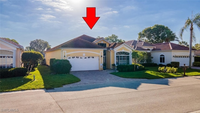 mediterranean / spanish home featuring a tile roof, a front yard, stucco siding, a garage, and driveway