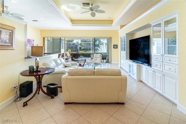 living room with visible vents, crown molding, ceiling fan, a tray ceiling, and light tile patterned floors