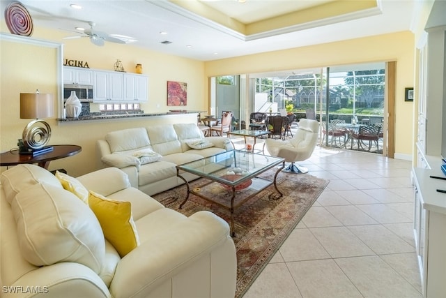 living room with a ceiling fan, a tray ceiling, recessed lighting, a sunroom, and light tile patterned floors