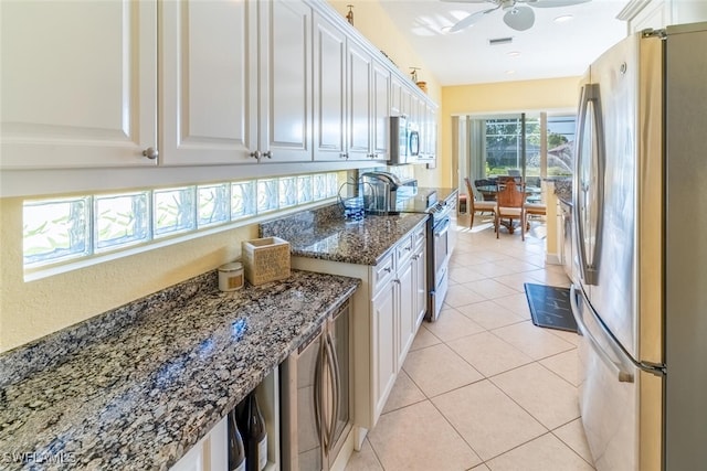 kitchen featuring light tile patterned floors, appliances with stainless steel finishes, white cabinets, and a ceiling fan