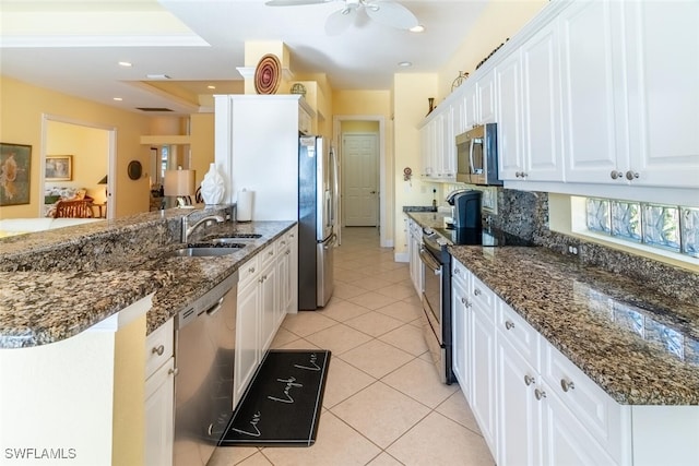 kitchen with a sink, stainless steel appliances, a peninsula, and white cabinets