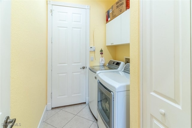 laundry room featuring light tile patterned floors, baseboards, cabinet space, and washing machine and clothes dryer