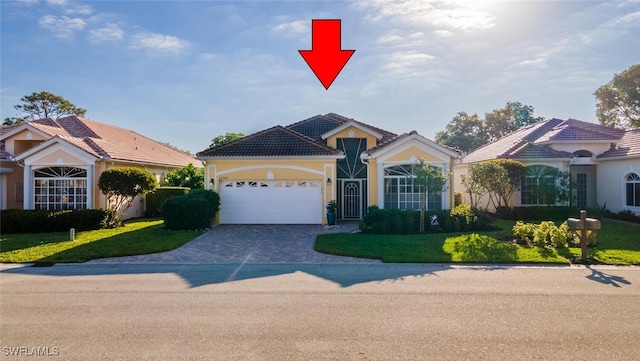 view of front of house with an attached garage, stucco siding, a front lawn, a tiled roof, and decorative driveway