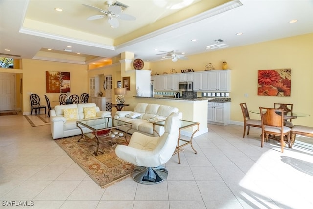 living room featuring a tray ceiling, light tile patterned floors, and ceiling fan