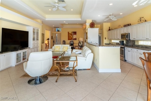 living room with light tile patterned flooring, recessed lighting, a raised ceiling, and a ceiling fan