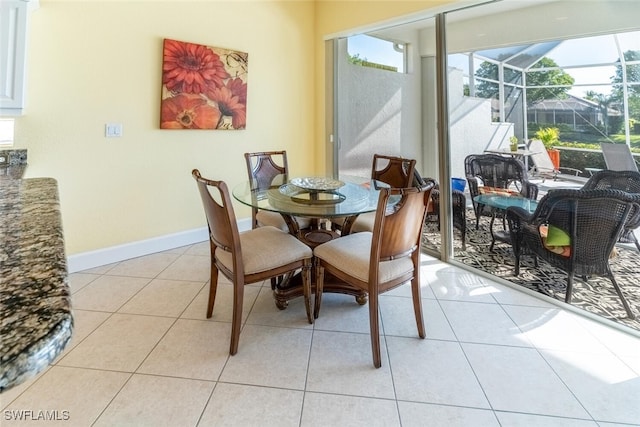 dining space with light tile patterned floors, baseboards, and a sunroom