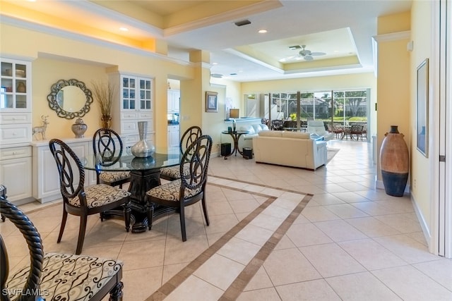 dining area featuring light tile patterned floors, a tray ceiling, baseboards, and crown molding