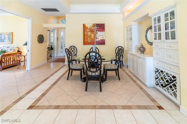 dining room with light tile patterned floors, a tray ceiling, baseboards, and crown molding