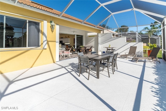 view of patio featuring outdoor dining area, a ceiling fan, and glass enclosure