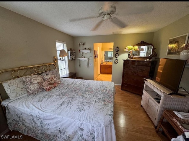 bedroom featuring ceiling fan, a textured ceiling, ensuite bath, and wood finished floors