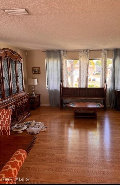 unfurnished living room with visible vents, a textured ceiling, and wood finished floors