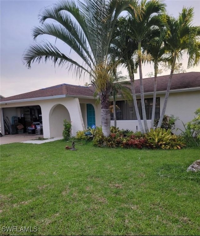 ranch-style house featuring stucco siding, an attached garage, concrete driveway, and a front yard