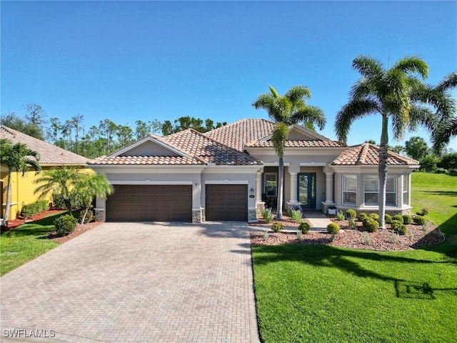 mediterranean / spanish-style house with decorative driveway, a garage, a front yard, and a tiled roof