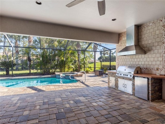 view of pool with a pool with connected hot tub, grilling area, glass enclosure, exterior kitchen, and a patio area