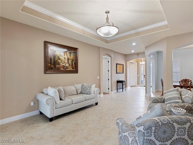 living room with a tray ceiling, arched walkways, light tile patterned flooring, crown molding, and baseboards